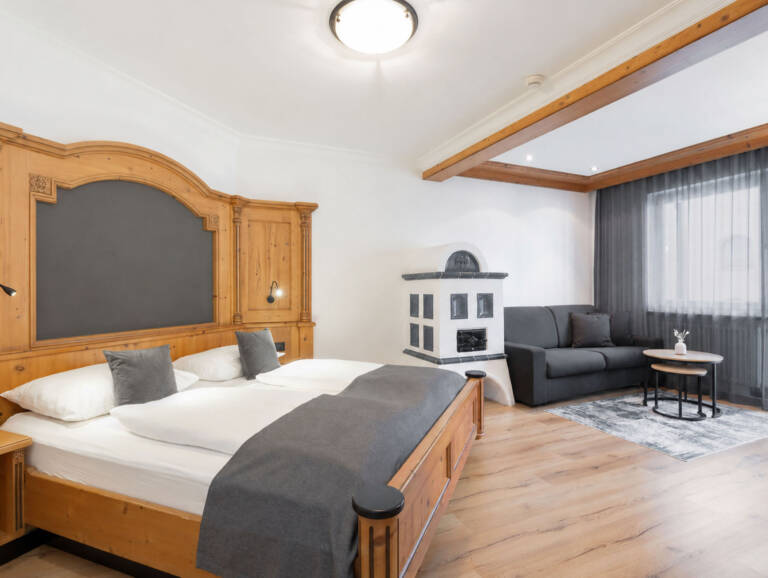 Double Room Deluxe w hotelu Montis – łóżko, część wypoczynkowa i piec kaflowy