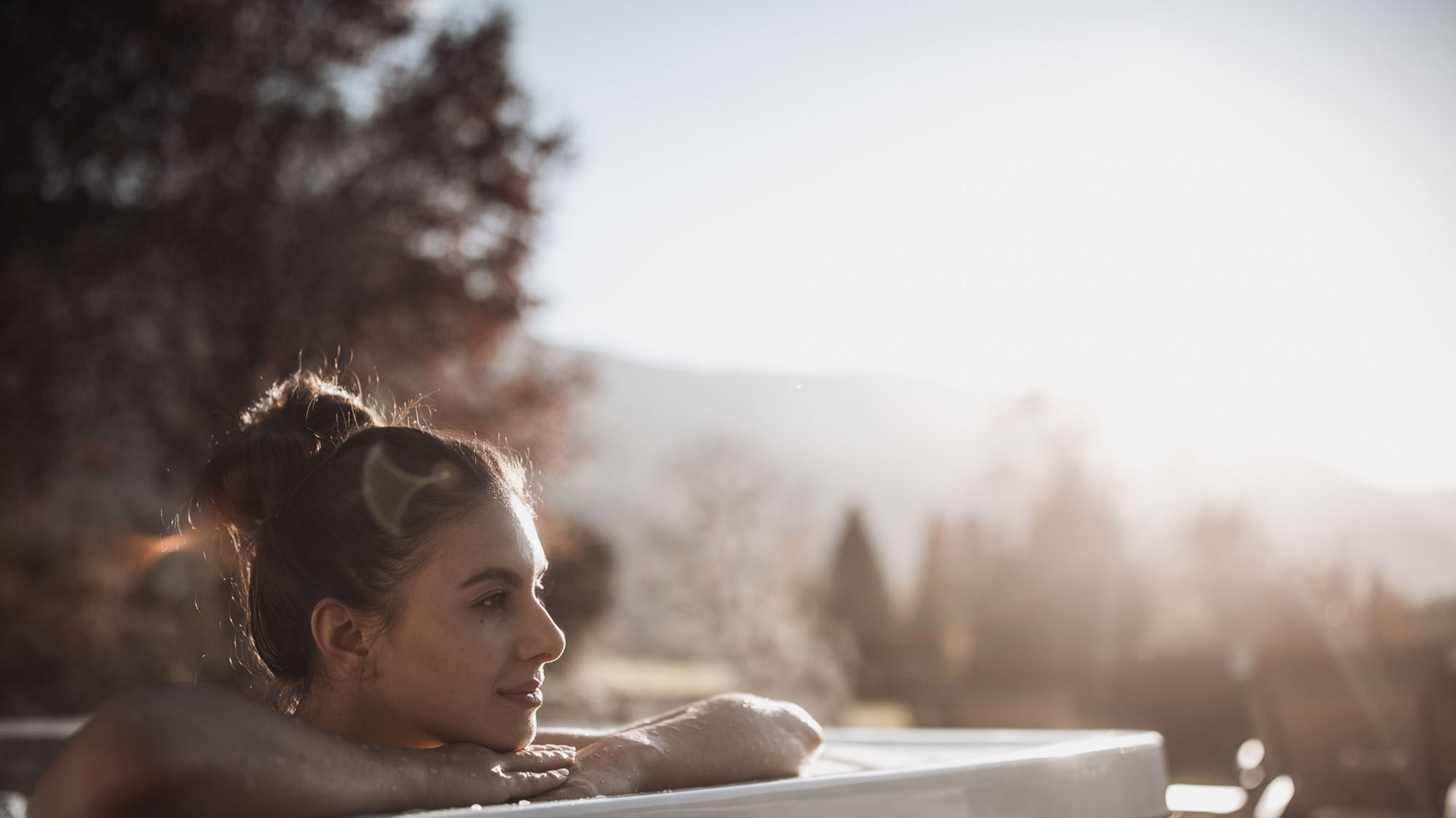 A woman sits in the outdoor whirlpool and gazes into the distance - Hotel Montis