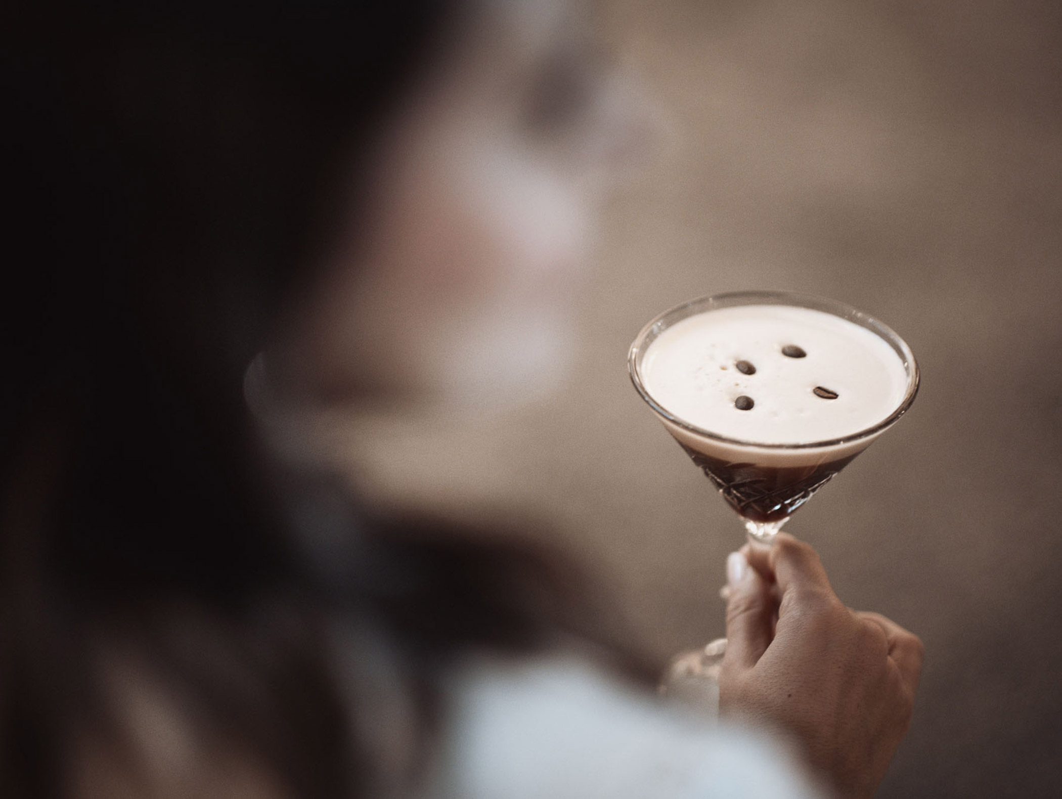A woman holds an espresso martini in her hand - Hotel Montis