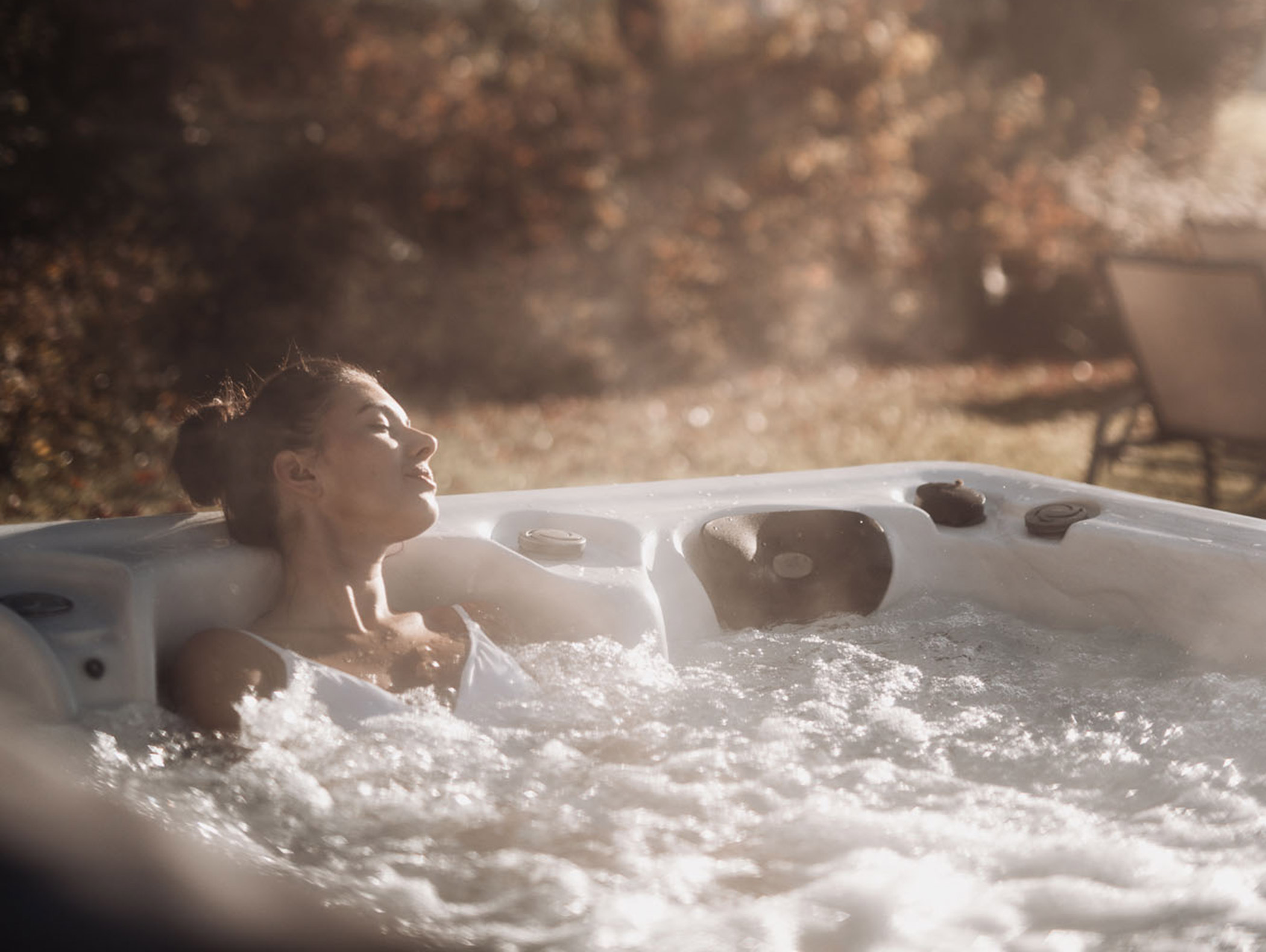 Eine Frau sitzt im Outdoor-Whirlpool und genießt die Sonnenstrahlen - Hotel Montis