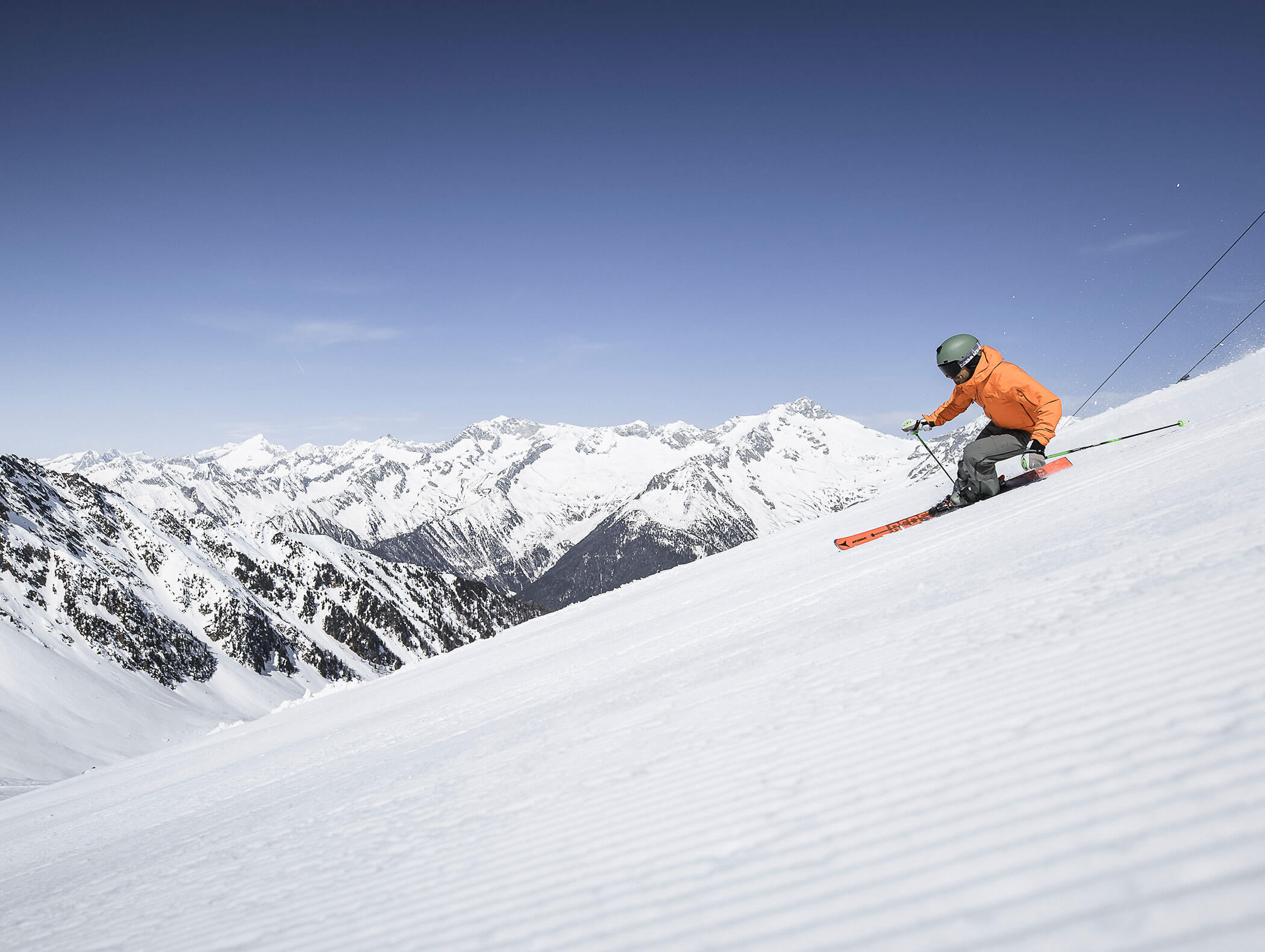 Ein Skifahrer bei der Abfahrt, dahinter die verschneiten Berge der Dolomiten - Hotel Montis
