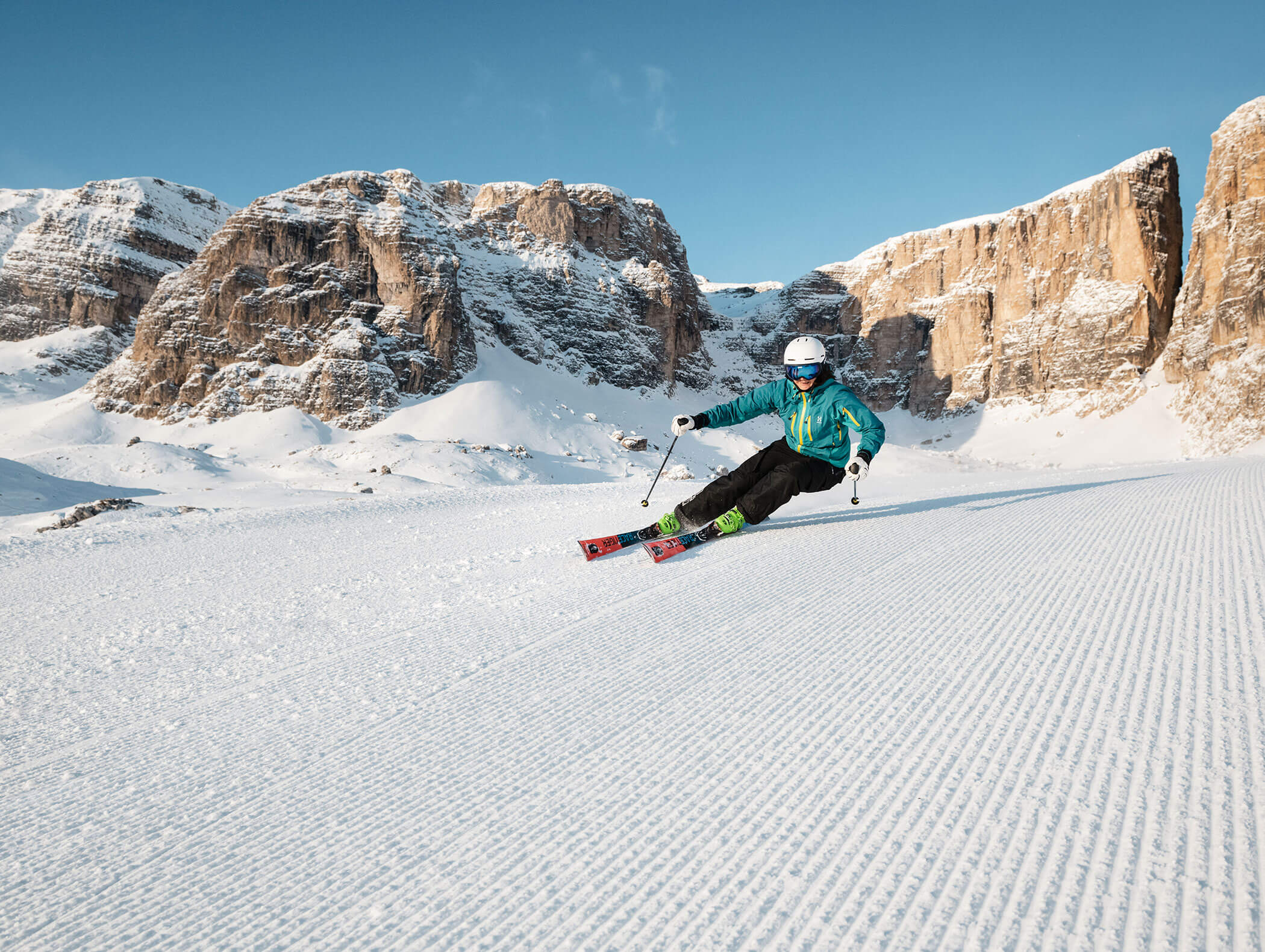 Eine Skifahrerin bei der Abfahrt, dahinter die markanten Dolomiten - Hotel Montis