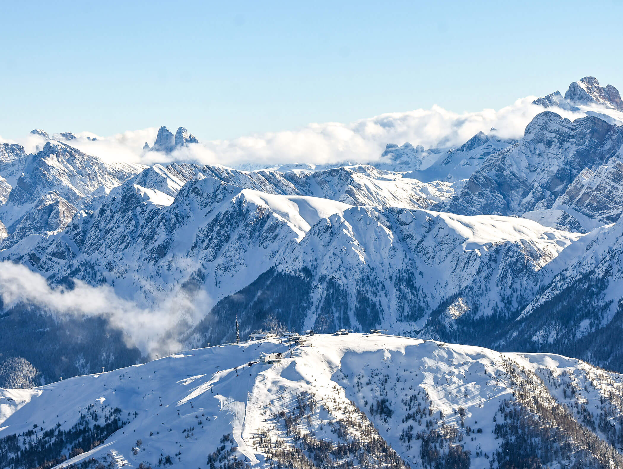 Drohnenaufnahme vom Gipfel des Skigebiets Kronplatz und die verschneiten Dolomiten dahinter - Hotel Montis