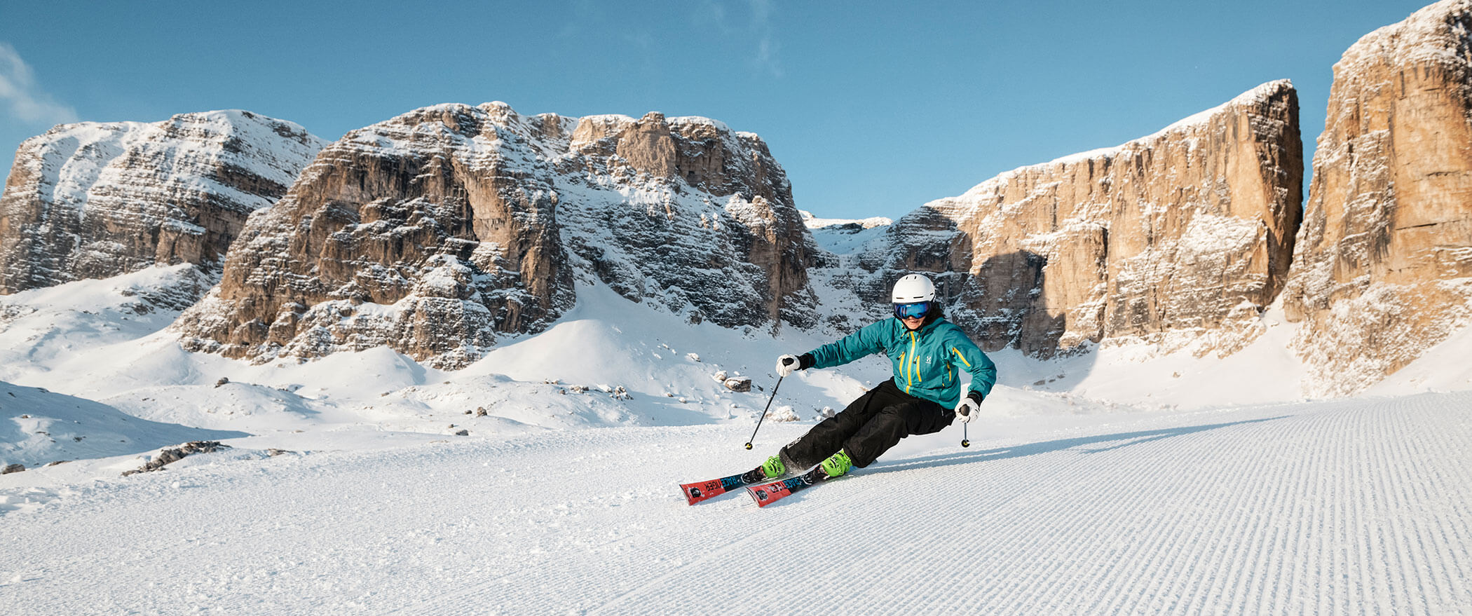 Eine Skifahrerin bei der Abfahrt, dahinter die markanten Dolomiten - Hotel Montis