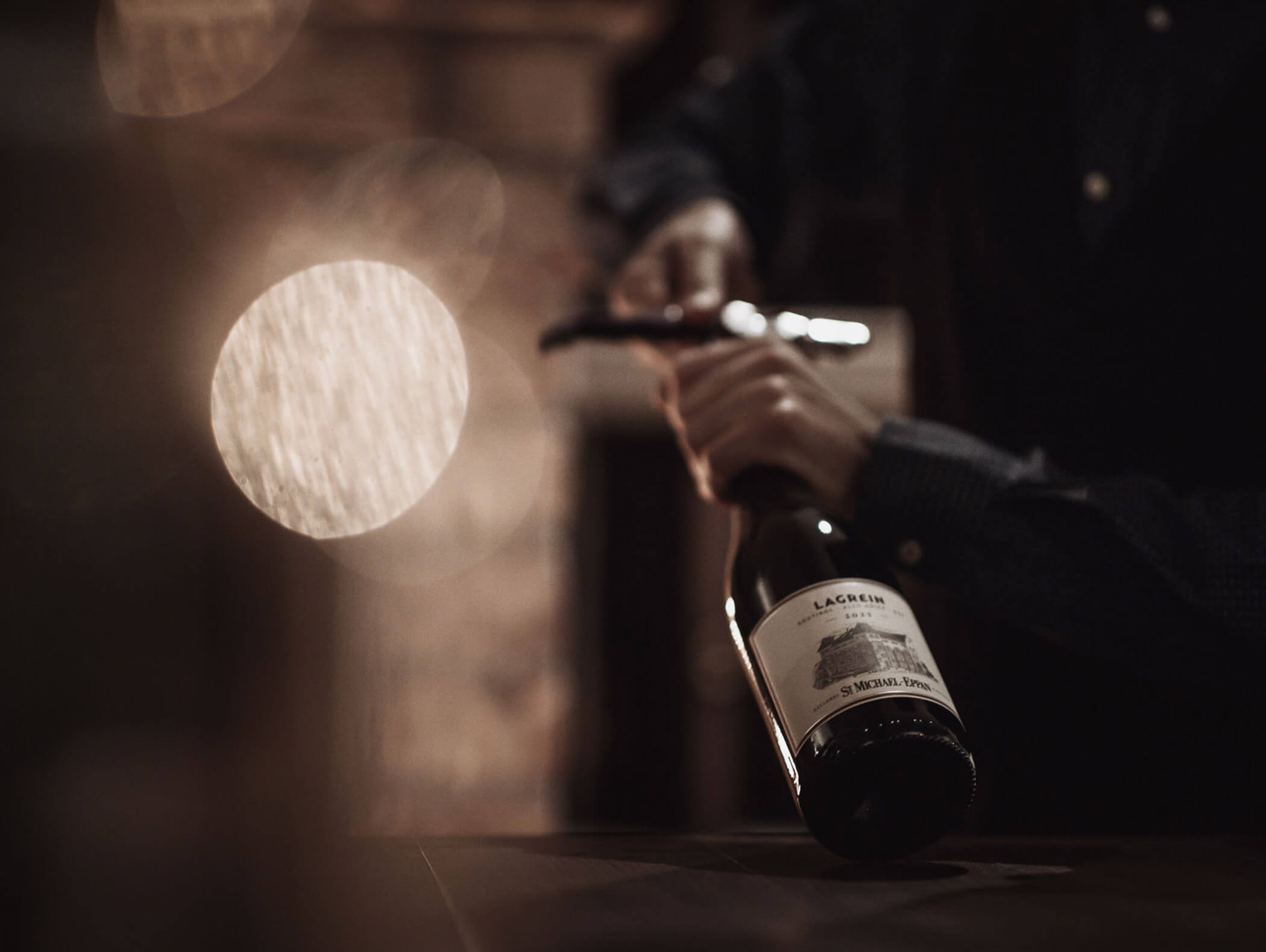 Ein Servicemitarbeiter öffnet eine Flasche Lagrein der Kellerei St Michael - Eppan - Hotel Montis